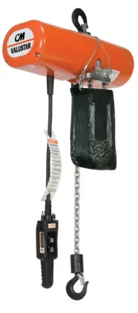 Orange CM Valustar electric chain hoist with a control pendant, black lifting hook, hanging chain bag, and warning label attached to the cord.